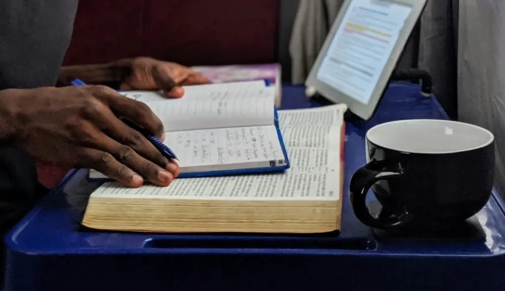 Mãos de homem sob livros e tablet ao lado em mesa