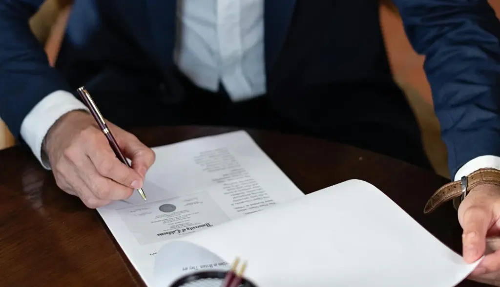 Homem de terno assinando documento