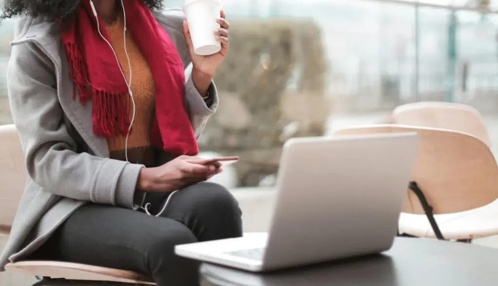 Mulher mexendo em computador e segurando café
