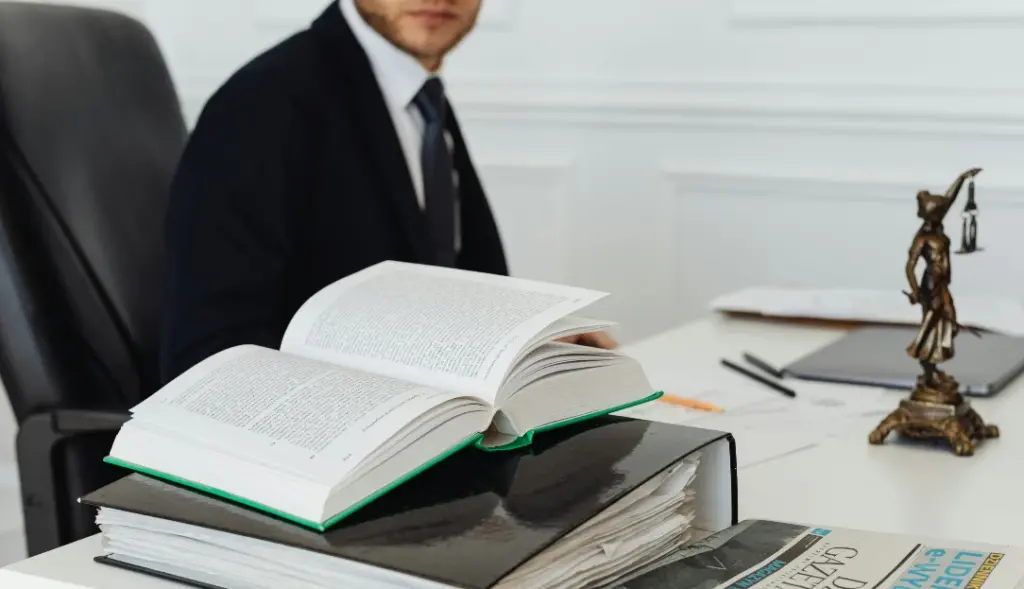 Mesa com livros e homem de ternoao fundo