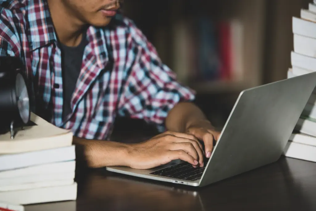homem digitando em notebook sobre a mesa