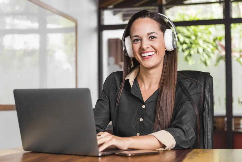 mulher sorridente com fones de ouvido em frente a um notebook